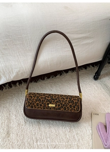 Detail of vintage leopard print baguette bag with golden metal buckle on ivory carpet