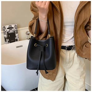 Detail of black pebbled leather bucket bag featuring gold hardware and drawstring closure