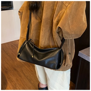 Détail du sac baguette noir minimaliste en cuir souple avec boucles dorées