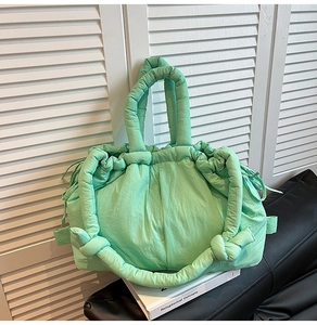 Close-up of light green quilted nylon tote bag featuring knotted padded handles