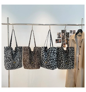 Dettaglio di borse tote con stampa zebrata e leopardata su un supporto con un trench beige