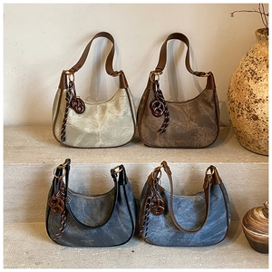 Detail of four vintage half-moon underarm bags with retro pendants on stone steps