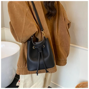 Detail of black pebbled leather bucket bag with gold hooks and drawstring closure