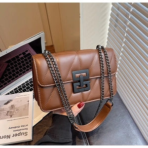 Detail of a brown quilted leather crossbody bag with a matte black chain and lock