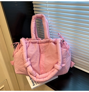 Detail of pink padded tote bag showing drawstring sides and soft quilted nylon texture