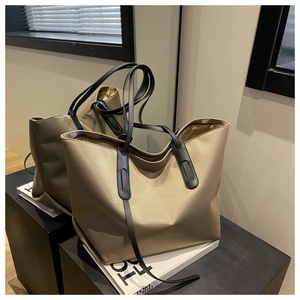 Détail d'un cabas en tissu oxford satiné avec poignées en cuir noir sur surface miroir