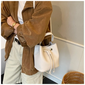 Close-up of cream bucket bag with litchi texture and gold metal adjustment buckles
