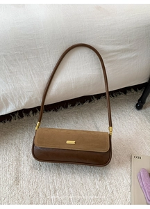 Close-up of retro brown bicolor baguette bag with gold lock and suede texture detail