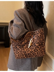 Large leopard print tote bag with brown leather handles and decorative beaded tassel