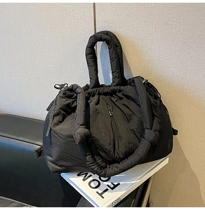 Detailed view of black quilted cloud bag with drawstring closure and front zipper pocket