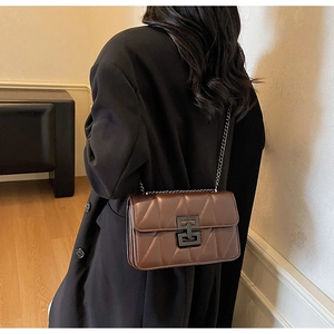 Detail of dark brown quilted chain bag featuring a black geometric turn-lock closure