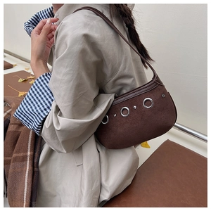 Brown suede underarm bag with metallic eyelets and leather strap worn with khaki coat