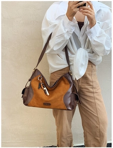 Detail of suede patchwork tote bag with bead tassel and metallic logo hardware