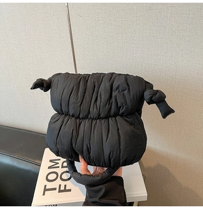 Detail of black quilted puffer bag showing soft padded texture and unique knot design