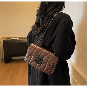 Detail of dark brown quilted crossbody bag with chunky black chain and geometric clasp