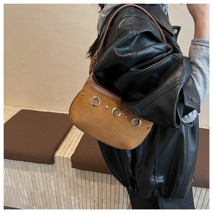 Detail of brown suede shoulder bag with silver eyelet metal decorations and a vintage vibe