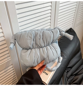 Detail of light blue padded cloud bag showing quilted fabric and knotted handle strap