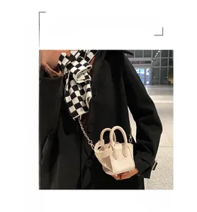 White lychee leather bucket bag with chain strap styled with black coat and scarf