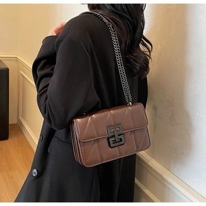 Detail of dark brown quilted crossbody bag featuring matte black square buckle and chain strap