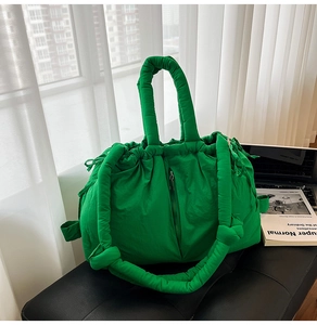 Detail of bright green quilted puffer tote bag with knotted strap on black seat