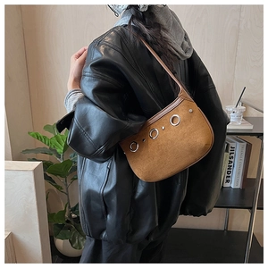 Detailed macro view of the brown suede underarm bag featuring decorative metal grommets