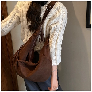 Detail of dark brown pleated hobo bag with adjustable silver buckle on wide strap