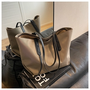 Détail du grand sac cabas en nylon kaki avec anses en cuir noir sur surface réfléchissante