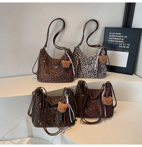 Detail of leopard print shoulder bags featuring plush bear charms and tassel zippers