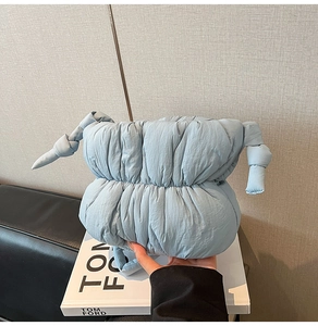 Detail view of light blue padded cloud bag with stylish knot design and nylon texture
