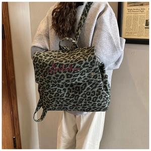 Detailed view of green leopard canvas backpack with red script logo embroidery on back