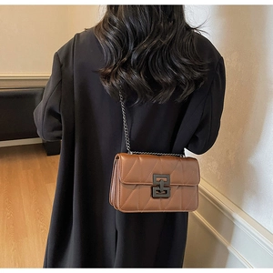 Detail view of caramel brown quilted shoulder bag with dark metal chain and twist lock