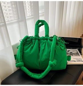 Detail of light green puffy nylon tote bag with drawstring closure and vertical zipper detail