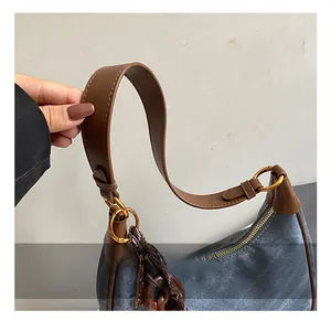 Detail of blue denim hobo bag with brown leather trim and golden ring hardware