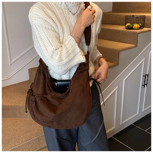 Detail of dark brown suede shoulder bag with drawstring folds on a lifestyle model