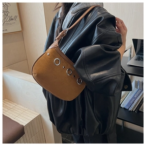 Detail of a brown suede handbag with decorative silver eyelets and metal rivets