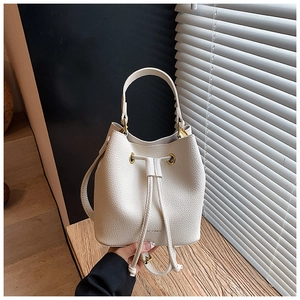 Detail of cream bucket bag showing lychee pattern leather and gold metal eyelets