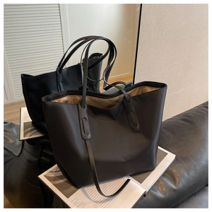 Détail d'un grand cabas noir en tissu Oxford montrant la texture nylon sur un canapé