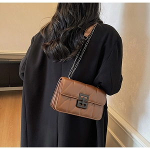 Close-up of brown quilted shoulder bag with geometric metal clasp and chain strap detail
