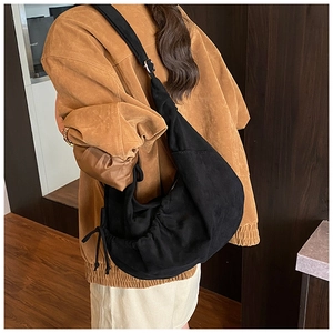 Detail of black crescent hobo bag with pleated design and adjustable shoulder strap on model