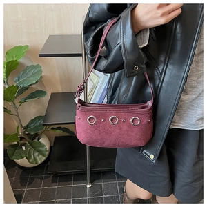 Detail of burgundy faux suede shoulder bag featuring silver metal rings and rivets