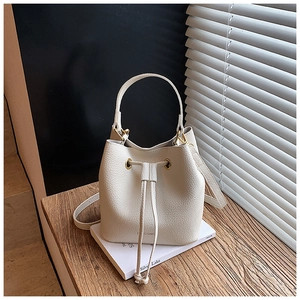 Detail of cream bucket bag in lychee leather with drawstring closure and handle