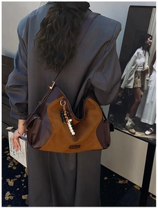 Detailed view of suede patchwork tote bag featuring stylish wooden bead pendant