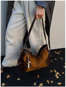 Detail of suede hobo bag with colorful bead charm and side pocket in autumn setting
