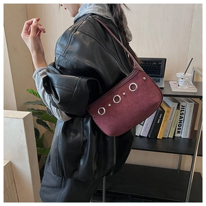 Detail of burgundy suede shoulder bag featuring large silver rings and metallic rivets