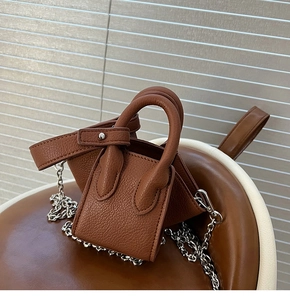 Detail view of brown lychee leather micro bag with silver chain on chair