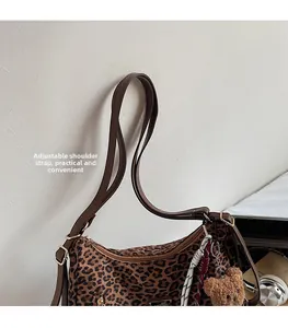 Close-up of leopard print shoulder bag with adjustable strap and plush bear charm