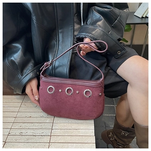 Detail of burgundy suede moon bag featuring silver hollow rings and studded decoration