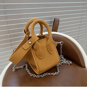 Close-up of mustard yellow pebble leather texture and silver chain on a mini bucket bag