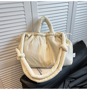 Close-up of cream quilted puffer tote with knotted shoulder strap and drawstring closure