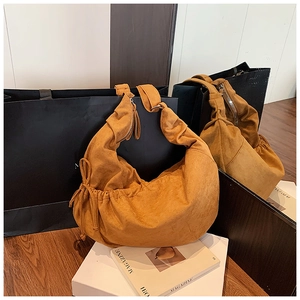 Detailed close-up of ginger suede pleated crescent bag with adjustable drawstring accents